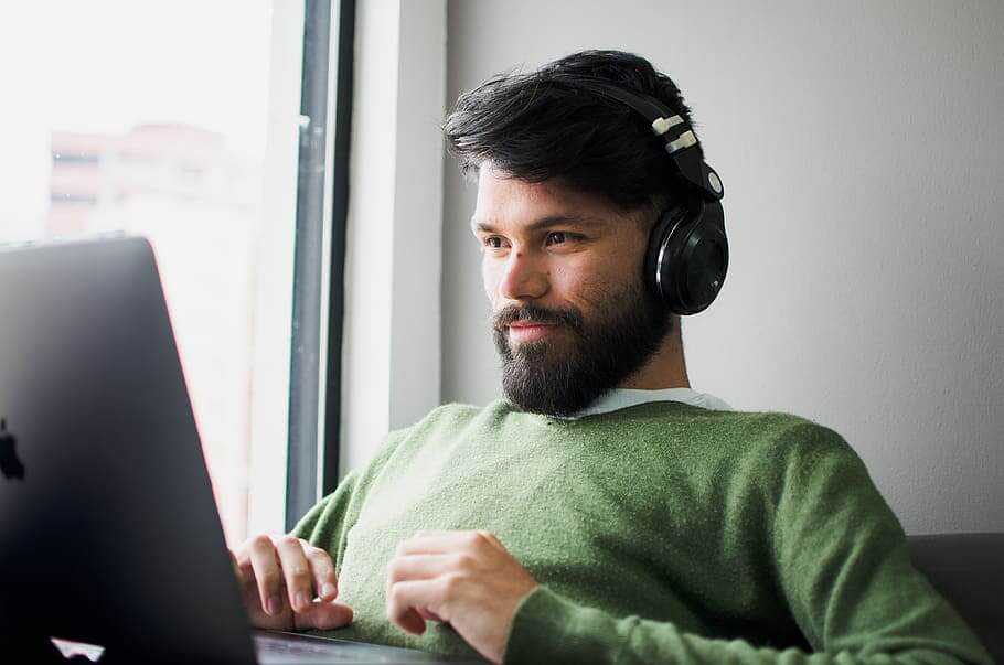Seorang pria memakai headphone sambil melihat laptop